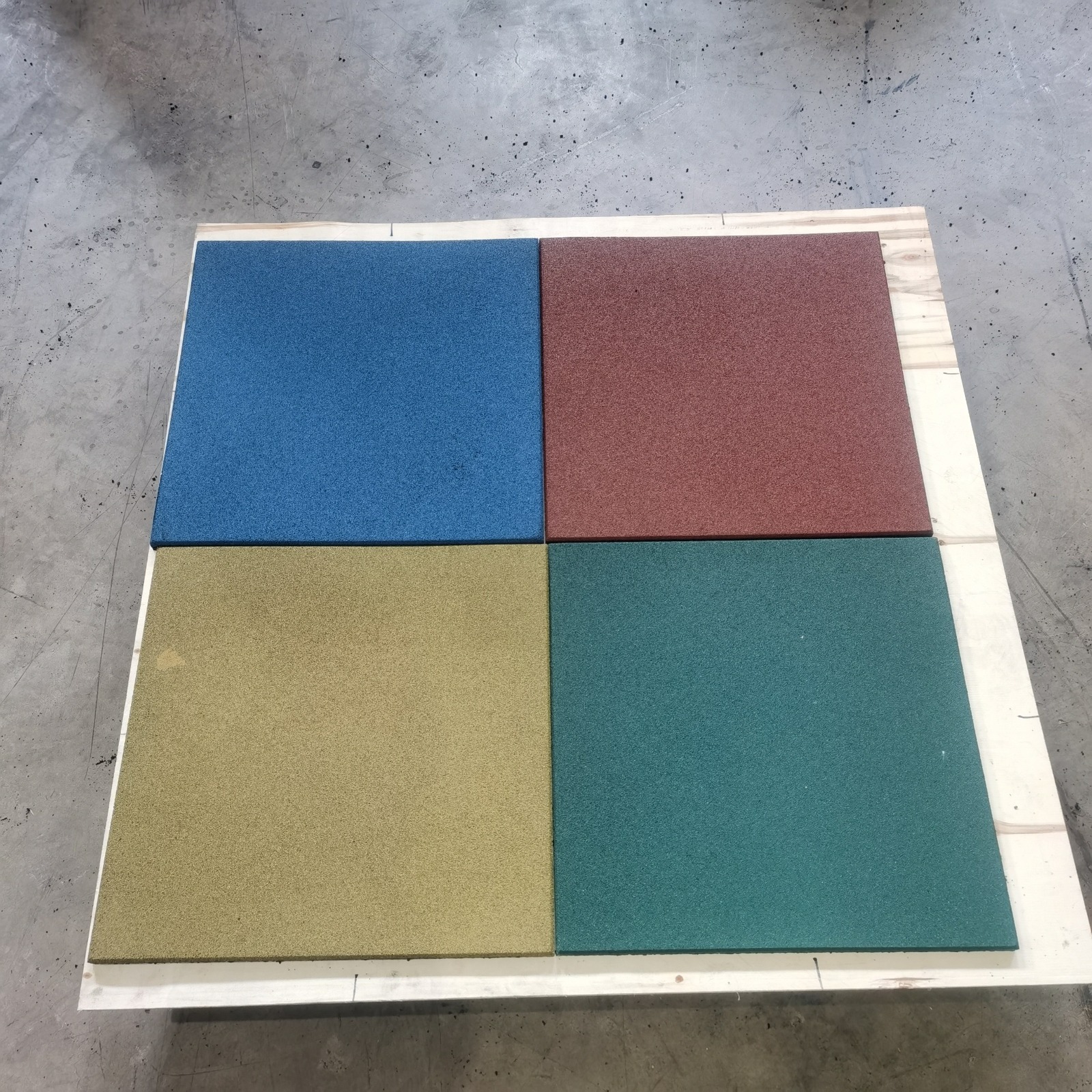 Blue red yellow and green rubber flooring sample tiles arranged as a four-tile board