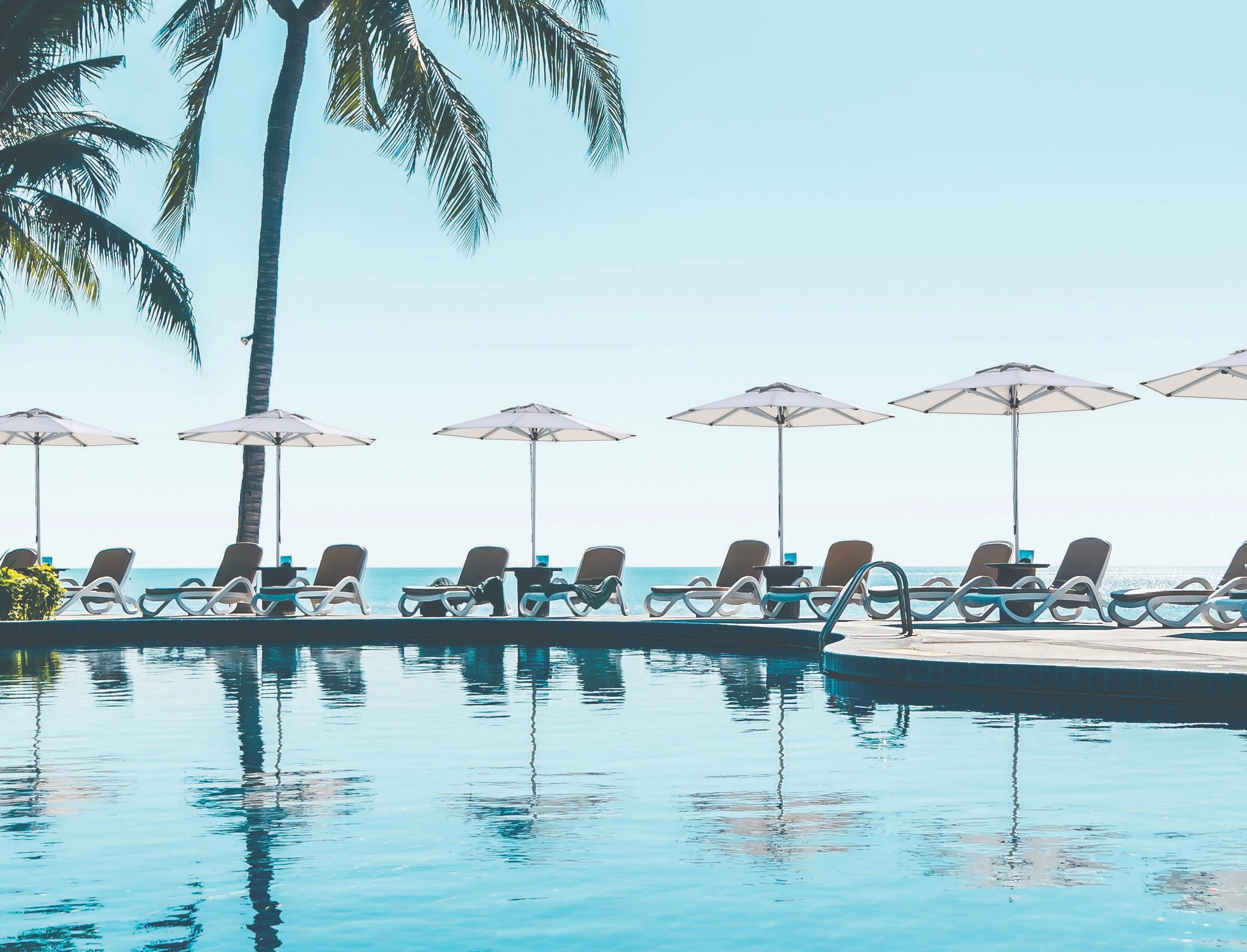 Shadowspec SU2 centre-pole umbrellas around a resort pool