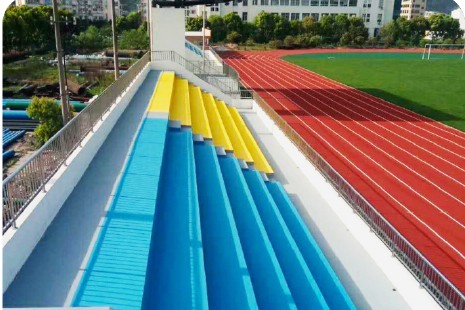 Blue and yellow public stadium terrace surface beside an athletics track
